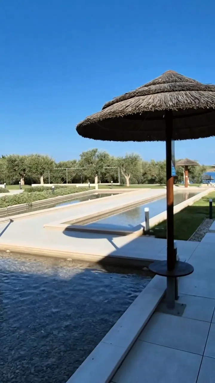 Bazen i suncobrani od trske uz more u resortu Del Mar Emotions, po danu prije večeri