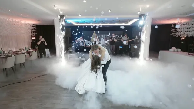 Mladenci plešu u niskom dimu ispred benda